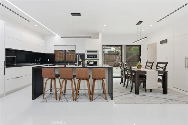 a kitchen with stainless steel appliances kitchen island granite countertop a table and chairs in it