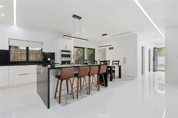 a kitchen with stainless steel appliances kitchen island granite countertop a table chairs and a refrigerator