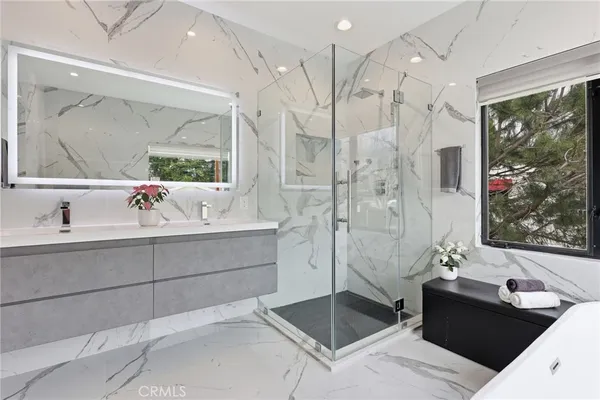 a large white bathroom with a tub a double vanity sink a mirror and a shower