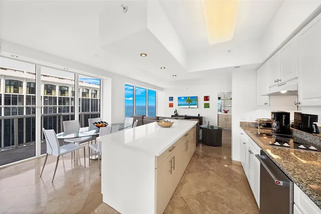 a kitchen with stainless steel appliances kitchen island granite countertop a stove a sink a dining table and chairs