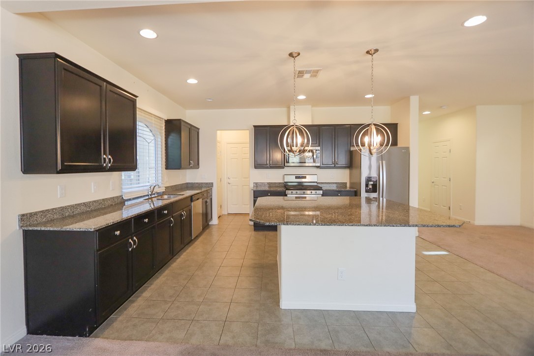 6418 Jackson Spring Road Las Vegas, NV 89118 - Photo 5 of 20 A well-appointed kitchen features dark cabinetry, granite countertops, and modern appliances, anchored by a spacious island.