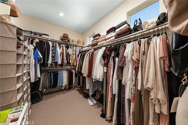 a view of walk in closet with clothes and shoes