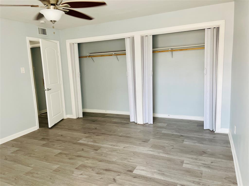 3121 Park Lane, Unit 1105 Dallas, TX 75220 - Photo 14 of 19 Unfurnished bedroom featuring two closets, wood finished floors, and a ceiling fan