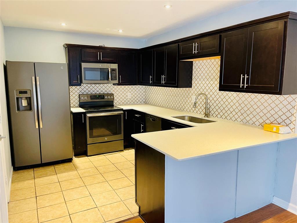 3121 Park Lane, Unit 1105 Dallas, TX 75220 - Photo 7 of 19 Kitchen with stainless steel appliances, light countertops, a peninsula, decorative backsplash, and light tile patterned floors