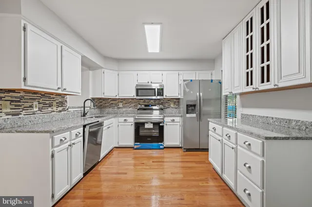 a kitchen with stainless steel appliances granite countertop a stove top oven a sink dishwasher and a refrigerator with wooden cabinets