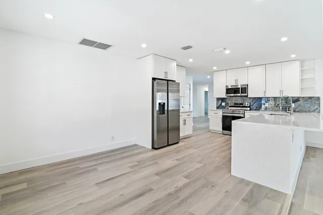 a kitchen with stainless steel appliances granite countertop a refrigerator sink and white cabinets