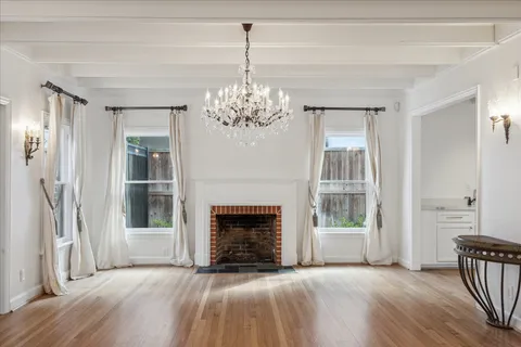 a view of a livingroom with wooden floor a fireplace and windows