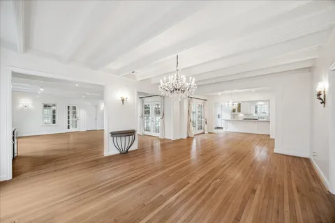 a view of an empty room and a kitchen with wooden floor