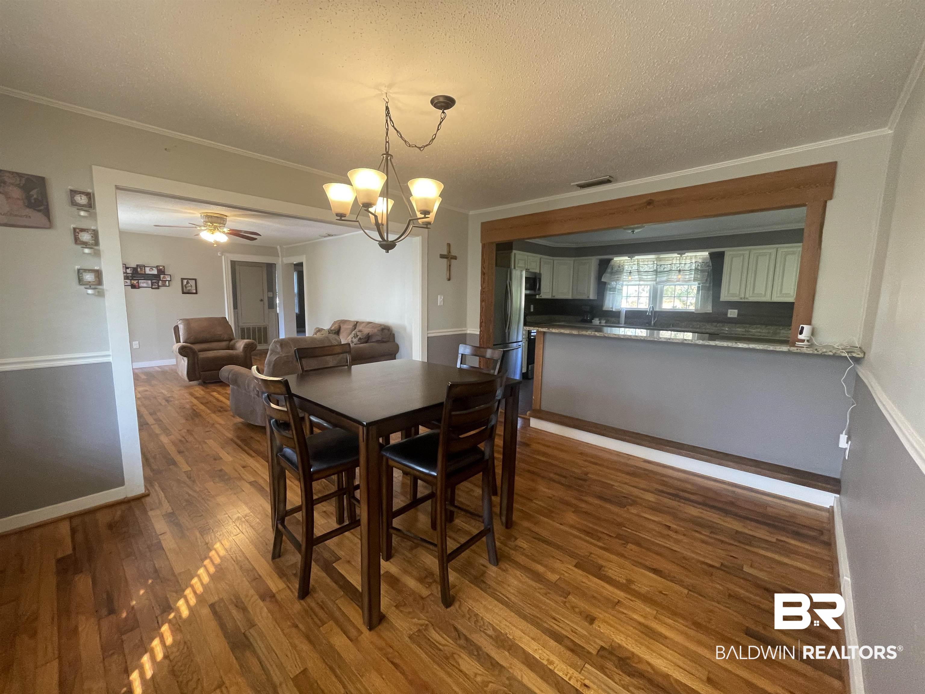 13850 Celeste Road Chunchula, AL 36521 - Photo 8 of 29 Dining room with dark wood-style flooring, crown molding, a chandelier, a ceiling fan, and a textured ceiling