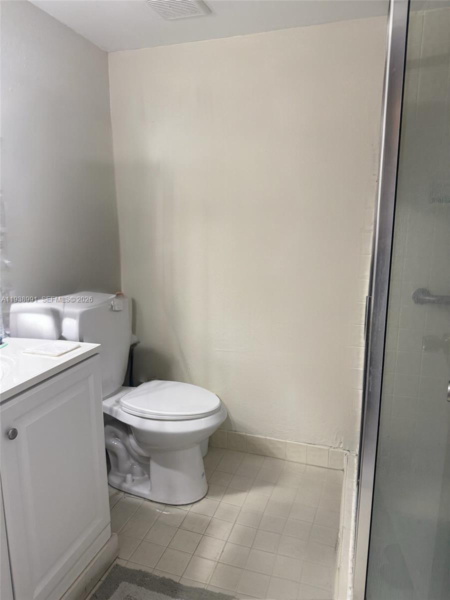 12209 Southwest 14th Lane, Unit 1101 Miami, FL 33184 - Photo 16 of 18 a white toilet sitting next to a white sink and vanity