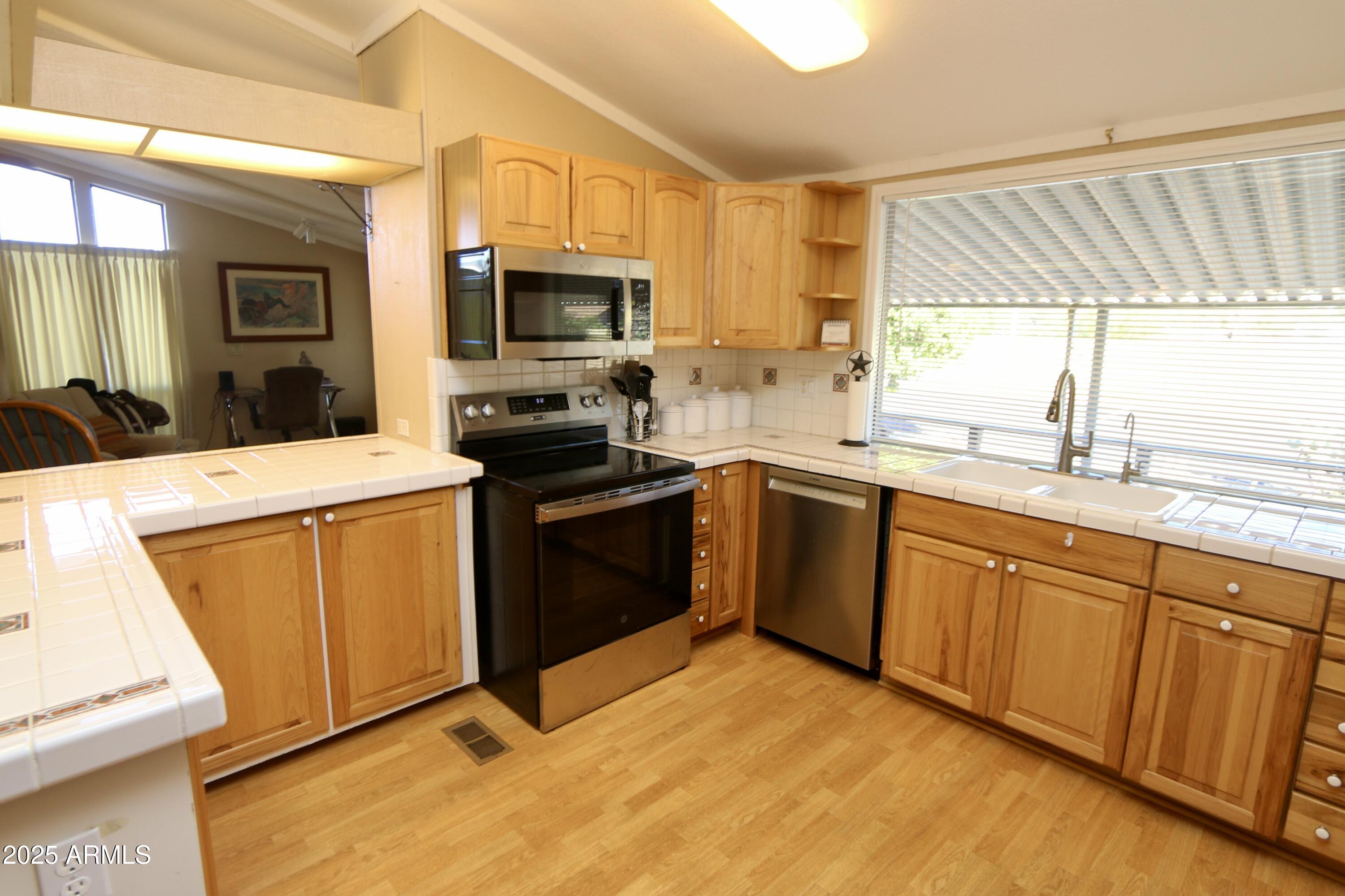 2701 East Utopia Road, Unit 208 Phoenix, AZ 85050 - Photo 2 of 22 a kitchen with stainless steel appliances granite countertop a sink a stove a refrigerator with grey cabinets and wooden floor