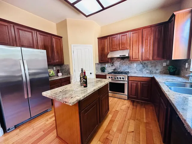 a kitchen with stainless steel appliances granite countertop a stove top oven a sink and dishwasher