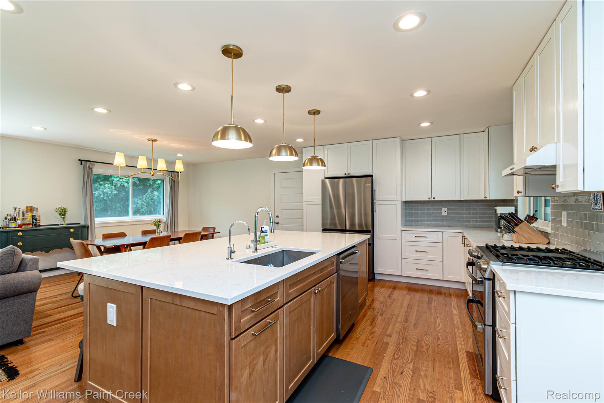 7093 Stonebrook Road West Bloomfield, MI 48322 - Photo 14 of 64 Expansive kitchen island with a light-toned countertop, integrated sink, and bronze pendant lighting