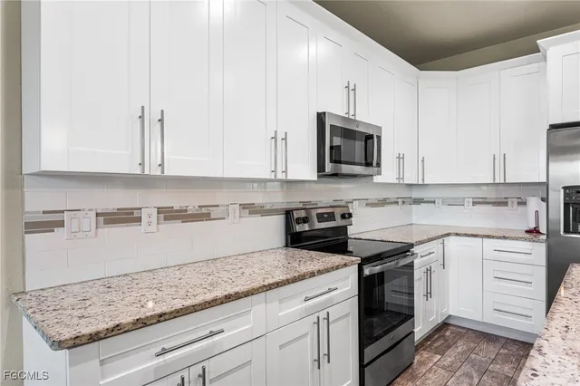 a kitchen with granite countertop white cabinets and white appliances