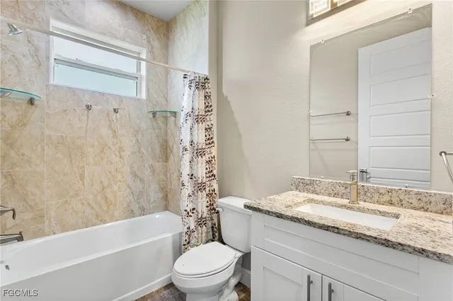 a bathroom with a granite countertop bathtub shower sink vanity mirror and toilet