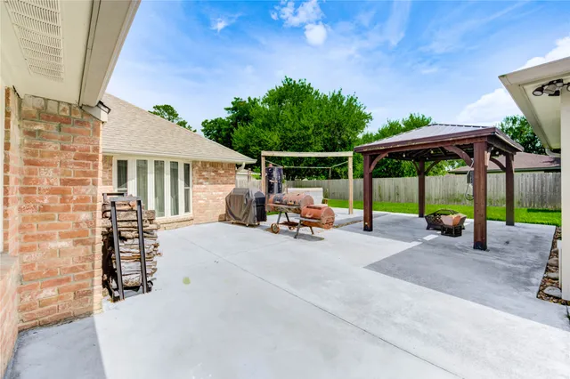 a view of a patio with table and chairs under an umbrella with a small yard