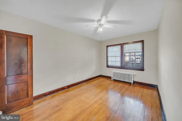 an empty room with wooden floor chandelier fan and windows
