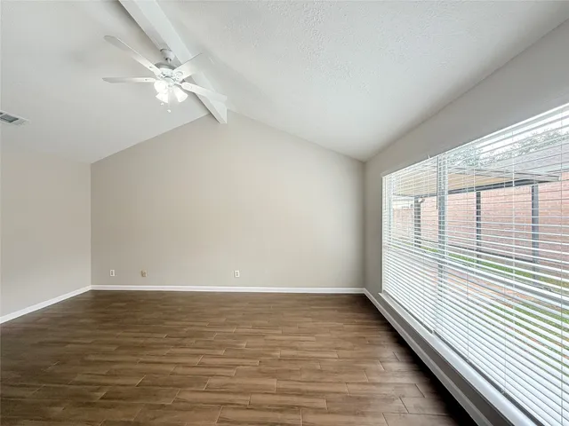 a view of an empty room with wooden floor and a window
