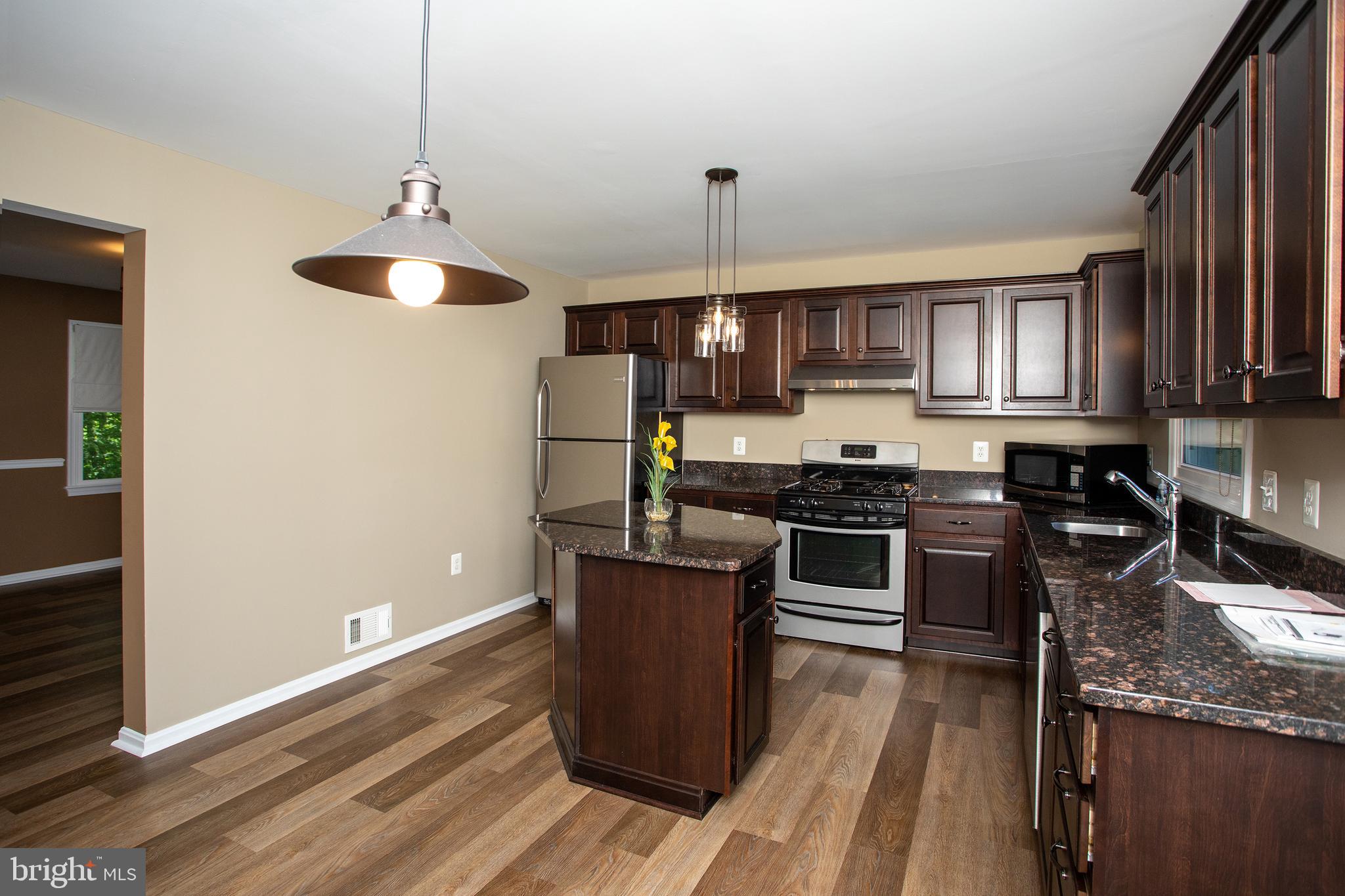 540 Thunderbird Drive Lusby, MD 20657 - Photo 32 of 66 a kitchen with granite countertop stainless steel appliances and wooden cabinets