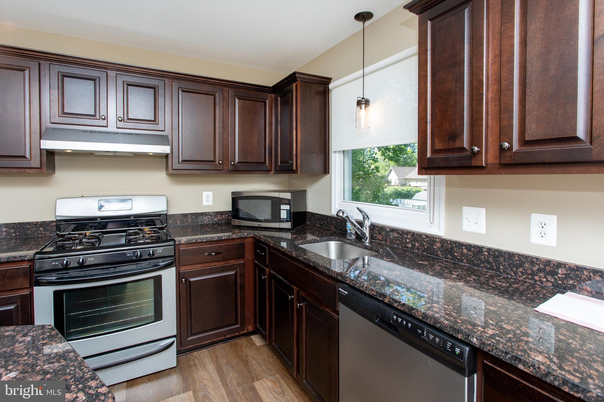 540 Thunderbird Drive Lusby, MD 20657 - Photo 33 of 66 a kitchen with granite countertop a stove sink and cabinets