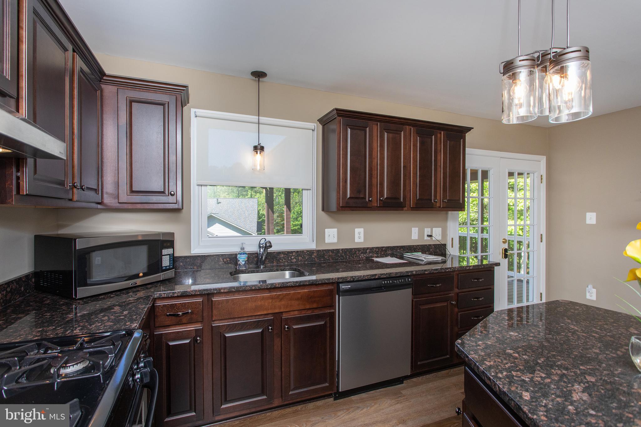540 Thunderbird Drive Lusby, MD 20657 - Photo 34 of 66 a kitchen with granite countertop stainless steel appliances a sink stove and cabinets