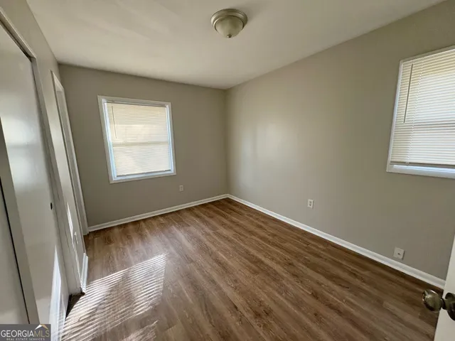 an empty room with wooden floor and windows