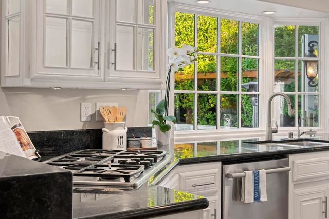 a kitchen with stainless steel appliances granite countertop a stove and a white cabinets