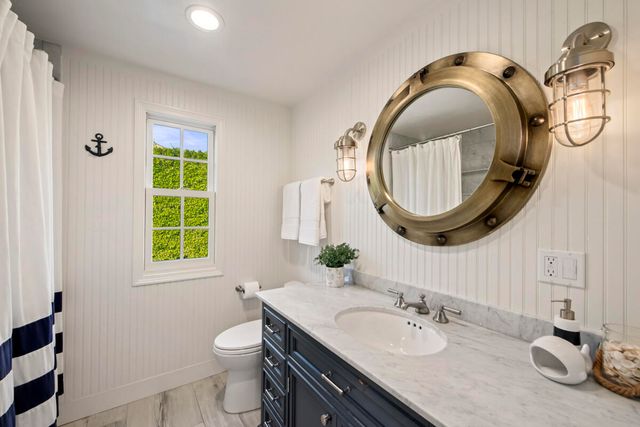 a bathroom with a granite countertop double vanity sink mirror and toilet