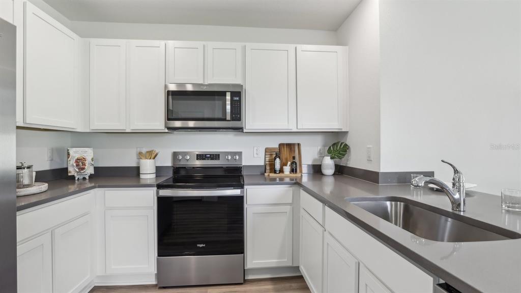 1046 Spotted Egret Loop Ruskin, FL 33570 - Photo 17 of 37 a kitchen with granite countertop white cabinets and stainless steel appliances
