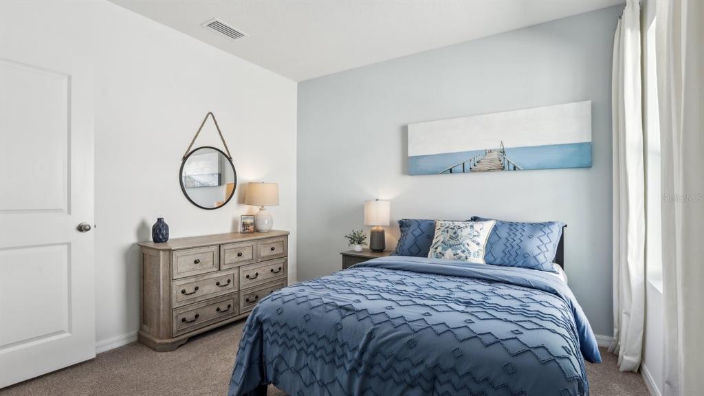 1046 Spotted Egret Loop Ruskin, FL 33570 - Photo 24 of 37 a bedroom with a bed a mirror and a lamp on dresser