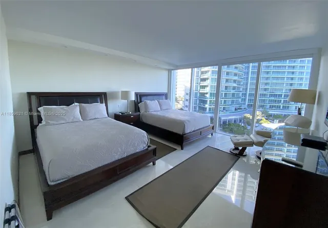 a bedroom with two beds and large windows