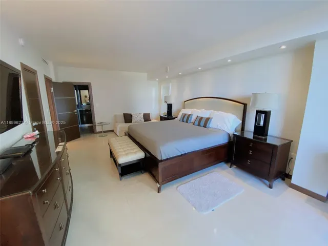 a bedroom with a bed and a flat tv screen on dresser