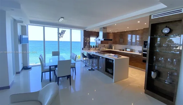 a kitchen with stainless steel appliances granite countertop a stove top oven a sink a dining table and chairs