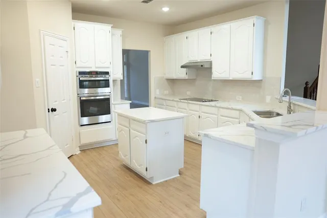 a kitchen with white cabinets and stainless steel appliances