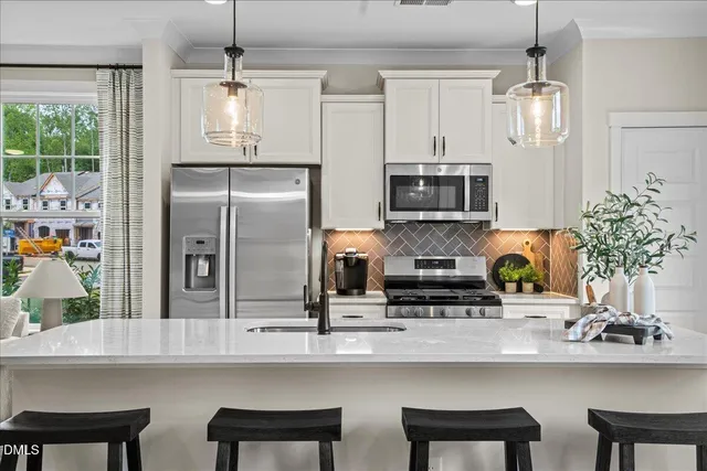 a kitchen with stainless steel appliances a table chairs refrigerator and microwave