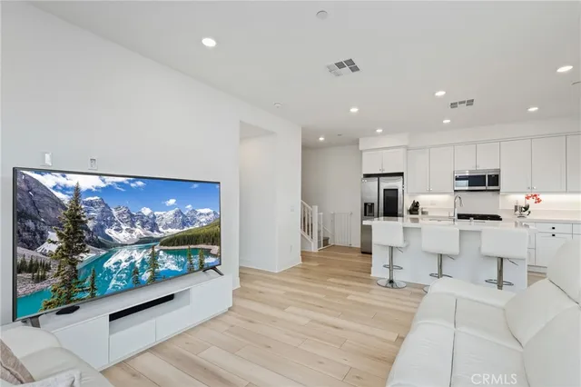 a living room with stainless steel appliances furniture and a flat screen tv