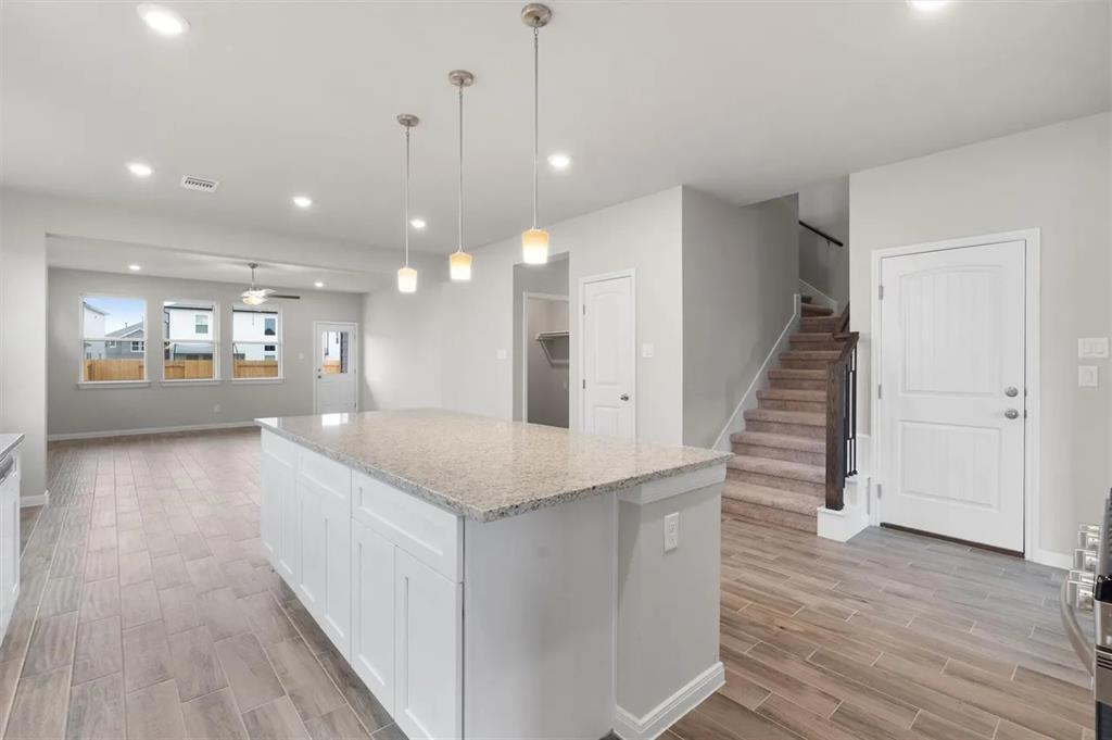 332 Stellar Wind Drive Georgetown, TX 78628 - Photo 29 of 29 A central kitchen island featuring granite counters anchors this inviting open floorplan, flowing seamlessly into the living space and staircase.