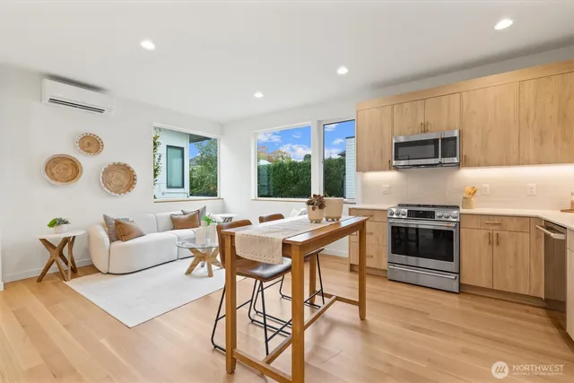 a kitchen with stainless steel appliances kitchen island granite countertop a stove top oven a sink a dining table and chairs with wooden floor