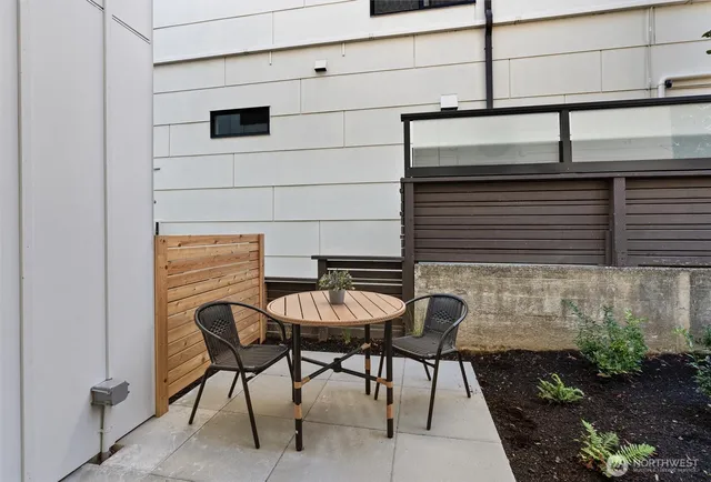 a balcony with table and chairs and potted plants