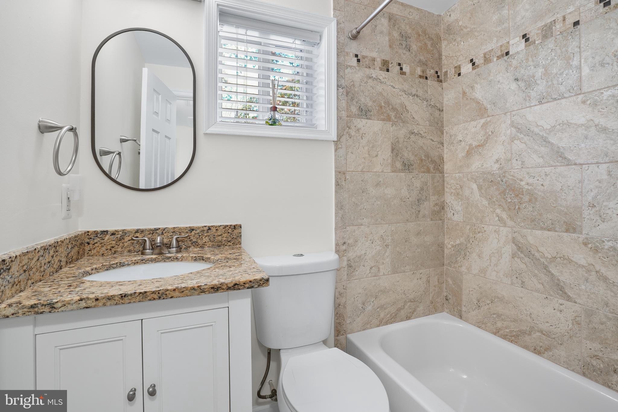 15709 Maple Drive Accokeek, MD 20607 - Photo 35 of 48 a bathroom with a granite countertop toilet a sink and a mirror
