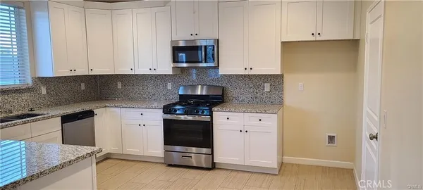 a kitchen with stainless steel appliances granite countertop a stove a sink and a refrigerator