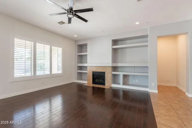 a view of an empty room with wooden floor fireplace and a window