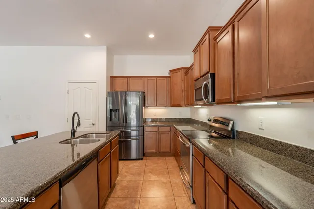a kitchen with stainless steel appliances granite countertop a sink a counter space and a window