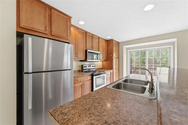 a kitchen with stainless steel appliances granite countertop a refrigerator a sink dishwasher with a stove and refrigerator