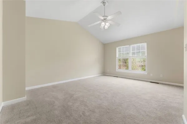 an empty room with a chandelier fan and windows