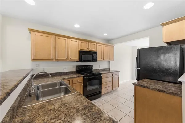 a kitchen with granite countertop a sink a counter top space stainless steel appliances and cabinets