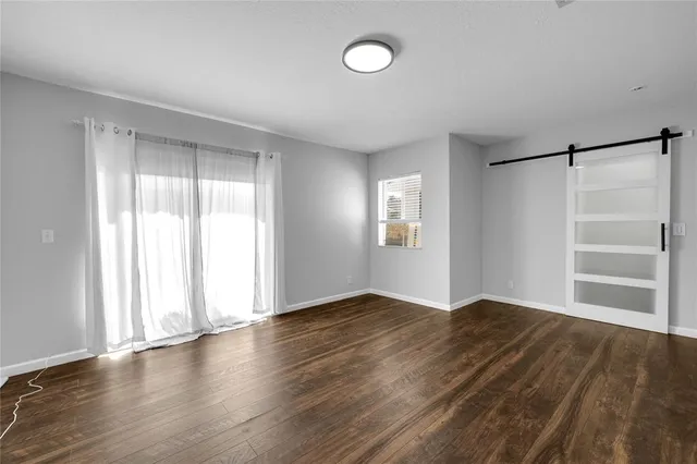 an empty room with wooden floor closet and windows