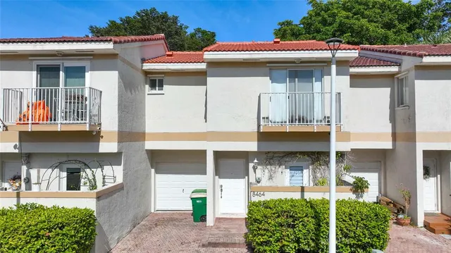 a view of a house with potted plants and a table and chairs