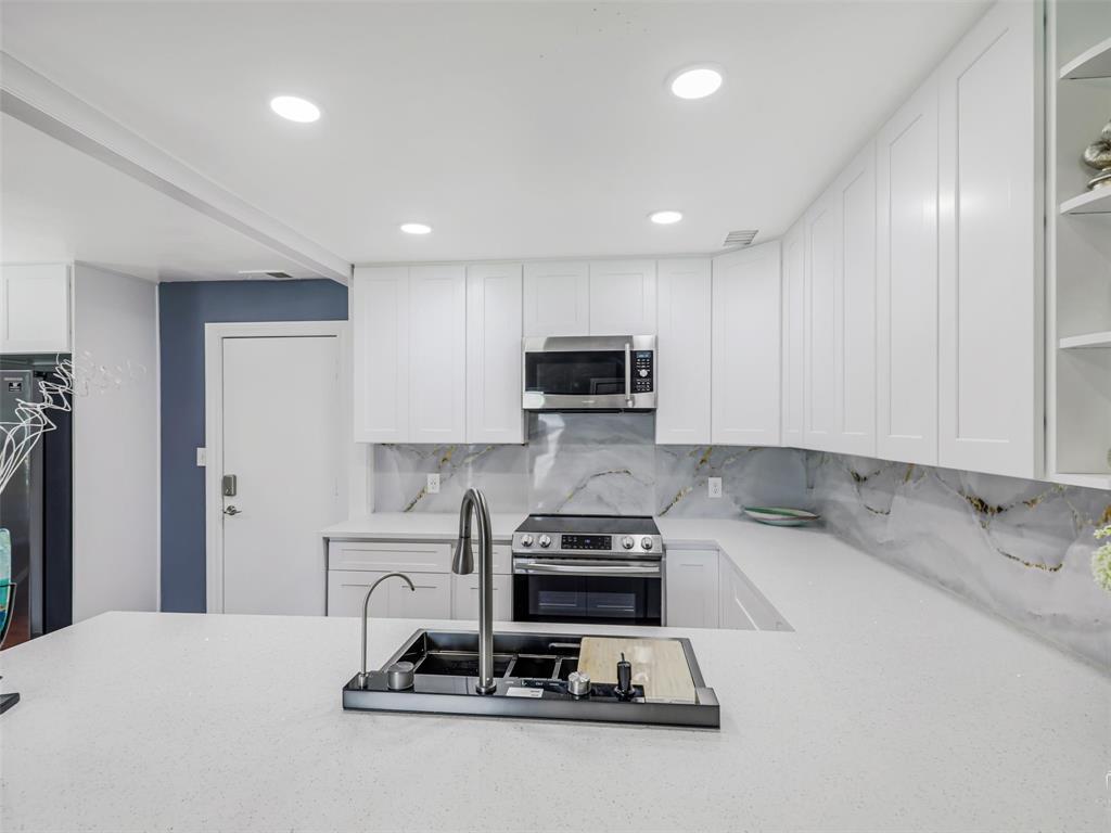 1716 East Parker Road Plano, TX 75074 - Photo 12 of 25 Contemporary kitchen featuring white shaker cabinetry, stainless steel appliances, a grey and gold veined backsplash, and recessed lighting