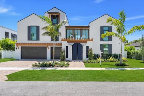 a front view of a house with a yard and potted plants